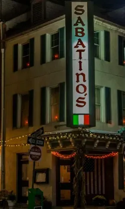 Sabatino's corner restaurant at night, neon sign glowing over string lights